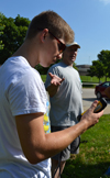 High School student Chieli Moldonado (left) reads the equipment during one of Wednesday's hands-on activities, as Walt Kelly (right) from the Illinois State Water Survey teaches campers how to analyze a water sample they have just taken from a well.