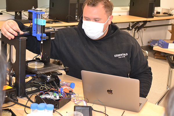 Joshua Whitely makes an adjustment to the 3D Bioprinter during the demo.