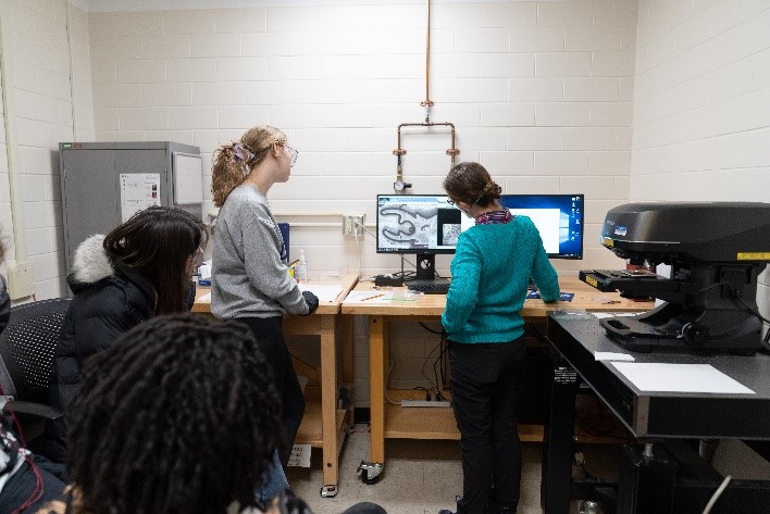 Dr. Julio Soares shows two students the fluorescence demonstration.