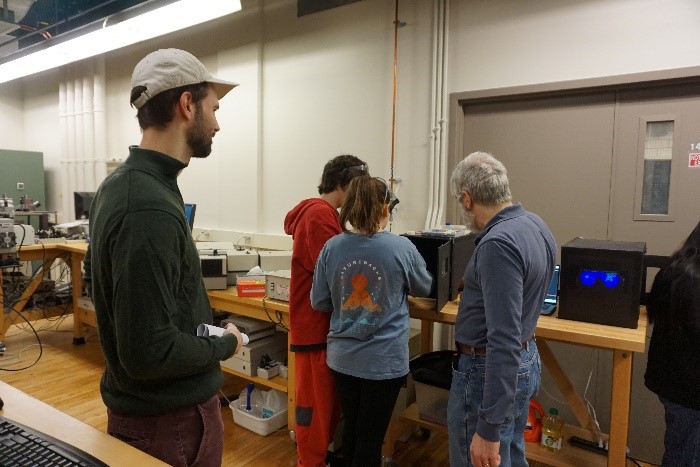 Dr. Julio Soares shows two students the fluorescence demonstration.