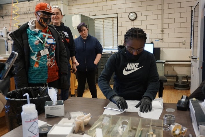 Dr. Julio Soares shows two students the fluorescence demonstration.