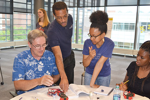  Lynford Goddard (third from the left) explains to Mahomet-Seymour science teacher, Terry Koker (left), how to complete the circut activity.