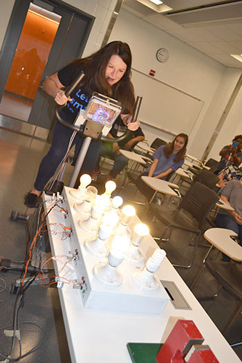 Sarah E. Goode STEM Academy’s arts instructor, Irica Baurer, gets all but the final bulb to light up when doing the stationary bike demo.