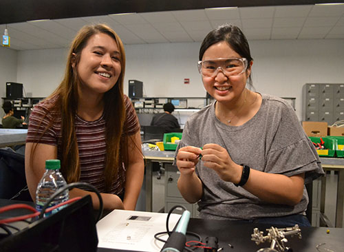   Goddard’s student, Kiran Murphy, gives Elizabeth Ohr, a science teacher at Urbana High School, some pointers while she solders her circuit.