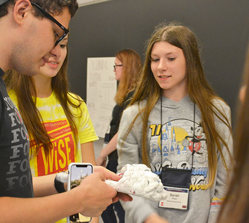 A visitor to the poster session examines the Plastic Group's prototype: the Skechie.