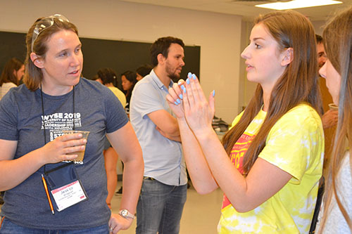 Jessica Krogstad (left) listens as a camper discusses her team's project during the Friday afternoon poster session.