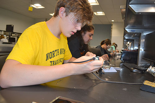 August Beck  solders the circuit he's making.