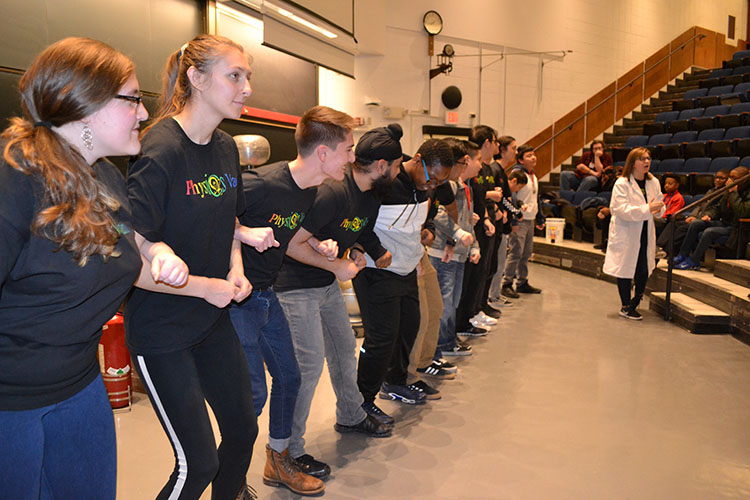 Spencer Hulsey (right) directs a demonstration where young Chicago students and Illinois Physics Van volunteers act out a gas heating up and expanding