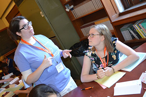   Grace Gaffe explains about a coding activity to a SIM camper.