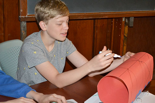 Samuel Balogh plays tic-tac-toe on a cylinder during the surfaces class