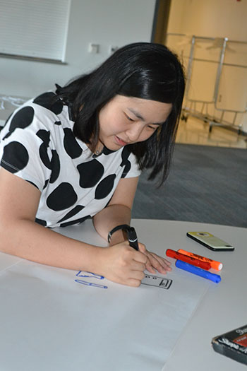 Elizabeth Ohr, a science teacher at Urbana High
School works on her team's poster comparing
what students think STEM is vs. what they think
it requires.