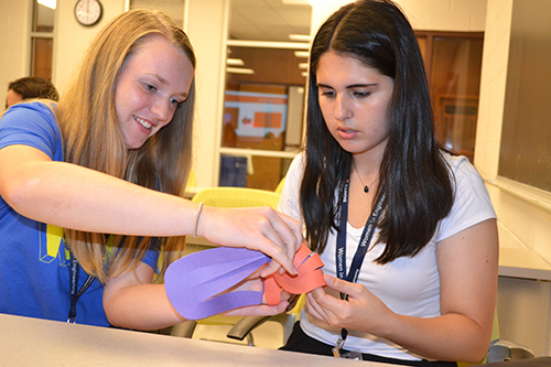 Two freshmen work on their paper heart.