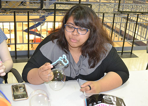 A high school student in WYSE camp blows a bubble using the unique-shaped wand she designed.