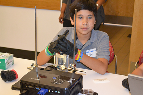 Olaya's third child, her son Elijah, listens to the instructions about how to do the 3D printing activity.