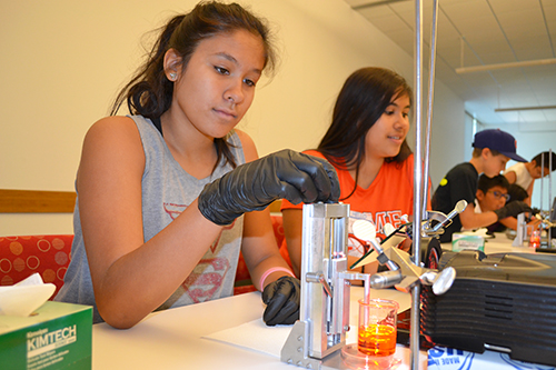 Areli Olayo (left), a local eighth grader adjusts the apparatus for the next level.