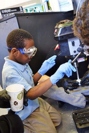 BTW kindergartener operates drill press to drill hole in his ping-pong ball mold.