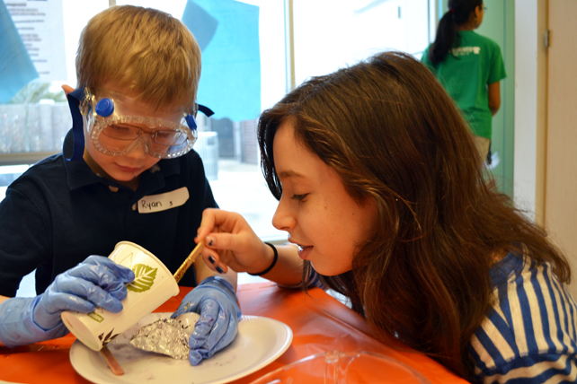 BTW kindergartener pours polymer into his mold with the help of a Next Gen middle school lab assistant.