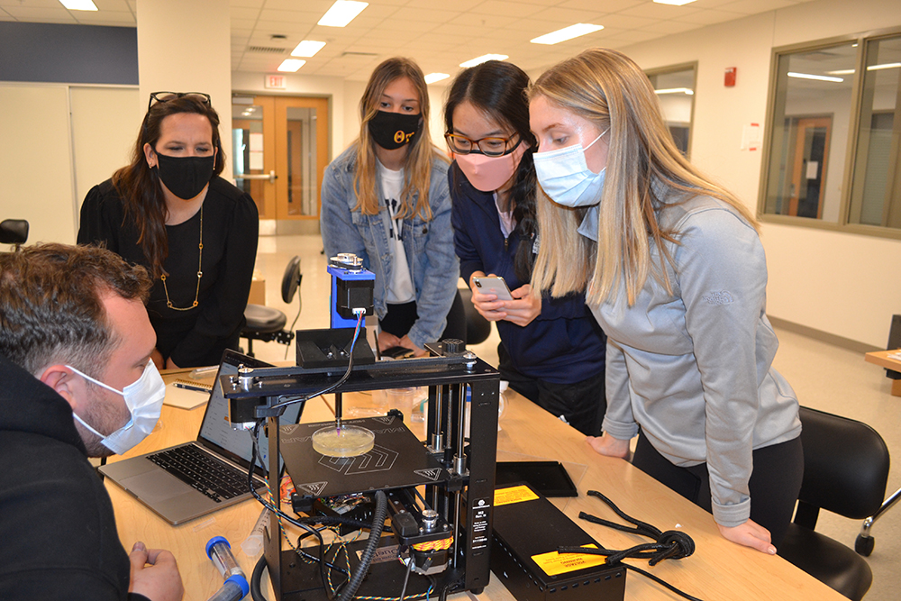Holly Golecki (second from the left) and the 3D Bioprinter team (left to right) Joshua Whitely, Lauren Ladehoff, Joy Chen, and Lauren Passwater, watch their printer during an imprompteau demo Golecki set up in one of BioE 435’s labs.