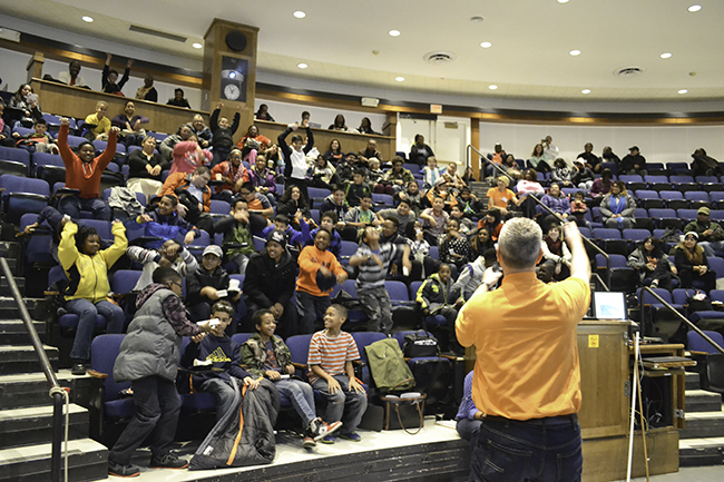  Kevin Pitts leads the students in "The Wave" during his Engineering SLAM! presentation about waves.