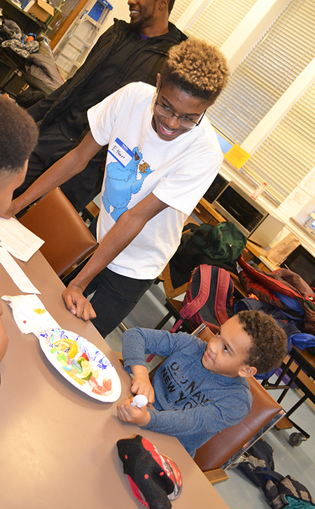 A Uni High student (center) interacts with a DREAAM House youngster who is sampling the fruit.