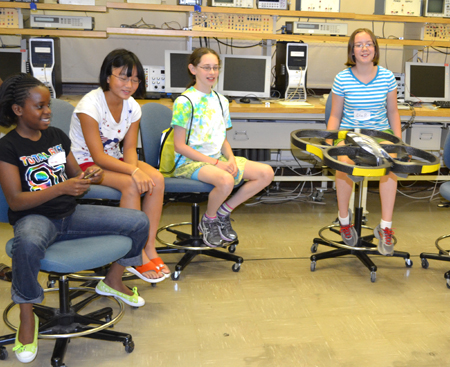 Camper flies radio-controlled helicopter fitted with bright yellow bumpers, to protect the students from injury.