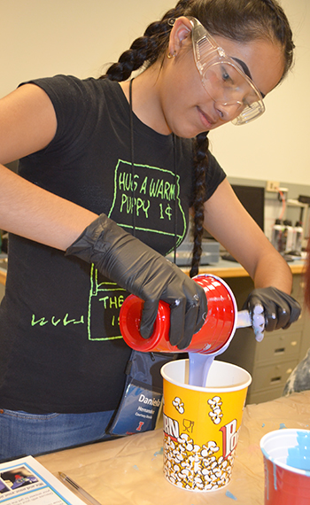 A GLAM camper pours polmer into a container to make a mold.