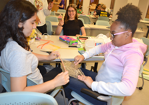 Two high schooers work on their design project with their material: saran wrap.