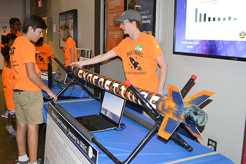 A member of Illinois Space shows a visitor their rocket they built.