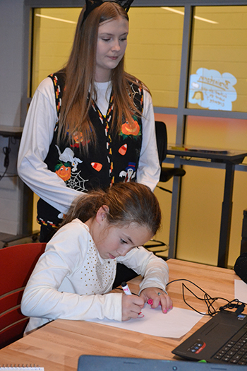 Mary Hadley helps a young visitor as she draws out her design.