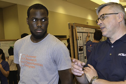 Prince Ghartey listens attentively as a critic converses with him about the data that the research group had accumulated and their overall presentation.