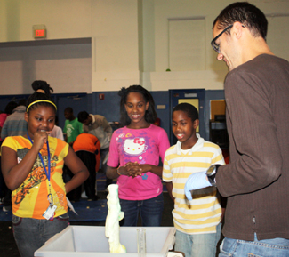 Physics 398SE grad student conducting experiement with middle school students.