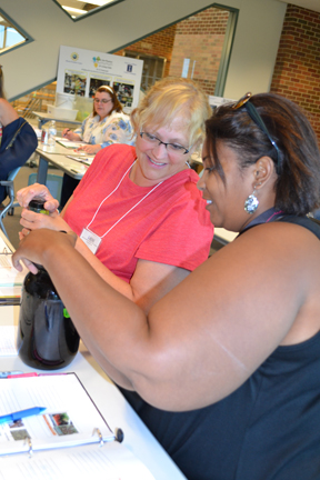 Two teachers at the iRISE workshop prepare to smell oil made from algae.