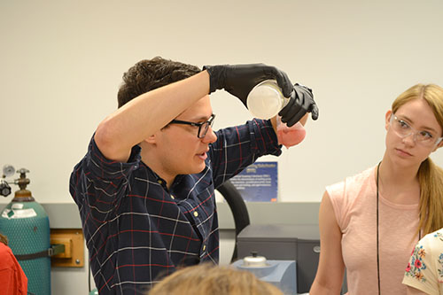 An Illinois grad student helping out with GLAM demonstrates a procedure during an activity where campers extracted DNA from strawberries. (Image courtesy of I-STEM undergrad Ryan Kim.)