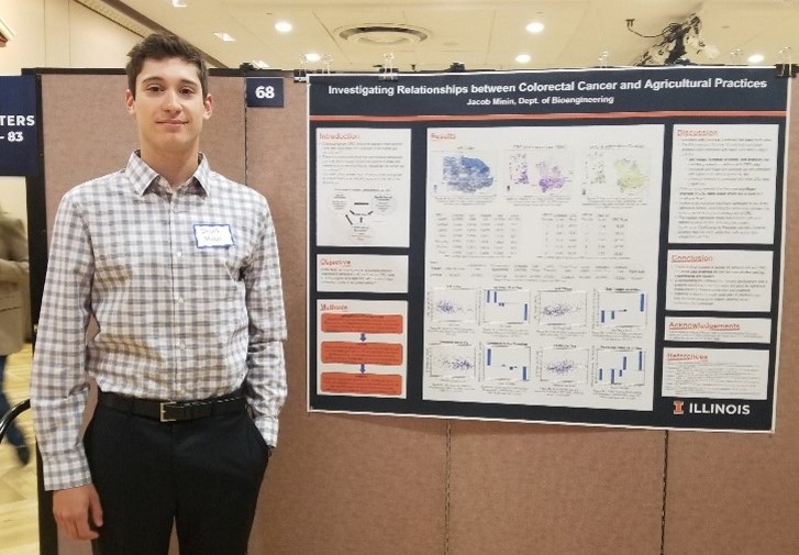 University of Illinois student Jacob Minin stands by a display of his research, which uncovers the relationship between farming practices to colorectal.
